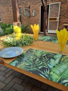 a wooden table with a plate and glasses on top of it at Gorgeous Gecko Guesthouse in Modimolle