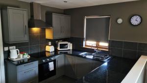 a kitchen with black counter tops and a clock on the wall at Chestnut Lodge, Summerhayes in Bridgwater
