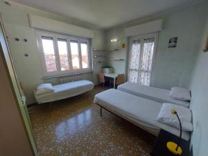 een slaapkamer met 2 bedden, een bureau en 2 ramen bij ASTI LOVELY APARTMENT in Asti