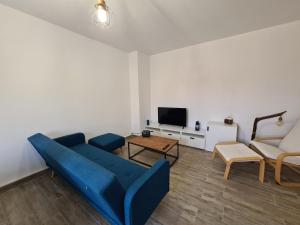 salon z niebieską kanapą i telewizorem w obiekcie Appartement rénové indépendant avec garage au centre du village w mieście Saint-Florent