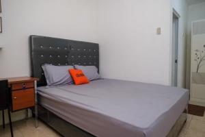 Una cama con una almohada naranja encima. en KoolKost Syariah near Luwes Gentan Park (Minimum Stay 30 Nights), en Sukoharjo