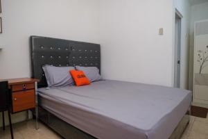a bed with an orange pillow on top of it at KoolKost Syariah near Luwes Gentan Park (Minimum Stay 30 Nights) in Sukoharjo