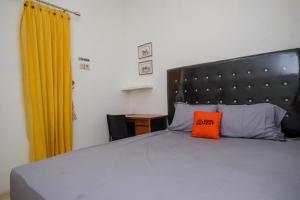 Una cama con una almohada naranja encima. en KoolKost Syariah near Luwes Gentan Park (Minimum Stay 30 Nights) en Sukoharjo