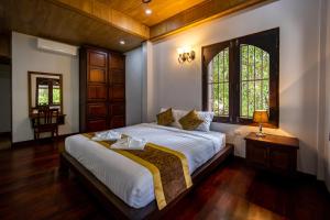 une chambre avec un grand lit blanc avec une fenêtre dans l'établissement Villa Mira Heritage, à Luang Prabang