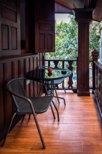 a patio with a table and chairs on a porch at Villa Mira Heritage in Luang Prabang