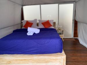 a bedroom with a bed with purple sheets and red pillows at Volcano rim Glamping Kintamani in Kubupenlokan
