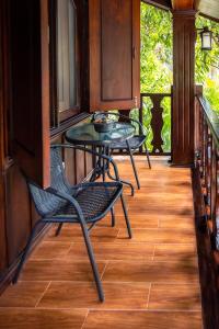 a porch with two chairs and a table at Villa Mira Heritage in Luang Prabang