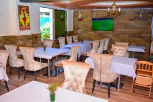 un ristorante con tavoli, sedie e TV di Omega Gardens Hotel a Karatina