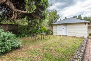 une cour avec des chaises et une table ainsi qu'un bâtiment dans l'établissement Centennial Cottage 2 - Botanica, à Bowral