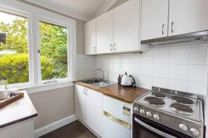 a kitchen with white cabinets and a stove top oven at Centennial Cottage 2 - Botanica in Bowral