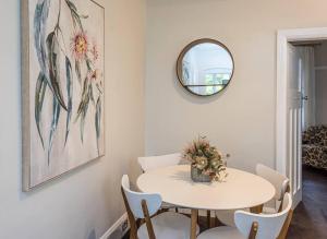 a dining room with a white table and a mirror at Centennial Cottage 2 - Botanica in Bowral