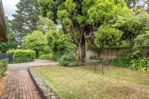 une cour avec une table, des chaises et un arbre dans l'établissement Centennial Cottage 2 - Botanica, à Bowral 3 autres photos
