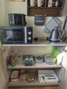 a kitchen with a microwave and some plates and dishes at Landhaus "Kühler Morgen", Appartement mit 140er Futonbett, Teeküche, Bad 