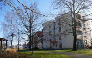 un gran edificio blanco con árboles delante de él en Sétány apartman en Mórahalom