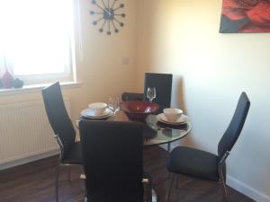 a dining room with a table with chairs and a clock at AB11 Apartments - Portland Street in Aberdeen