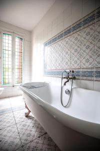 a white bath tub in a bathroom with blue and white tiles at Hôtel Terminus in Cahors