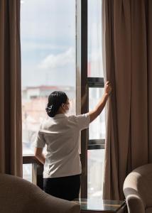 Una mujer está mirando por una ventana en Ironwood Hotel, en Tacloban