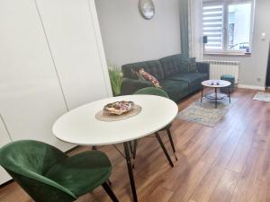 a living room with a white table and green chairs at Promenada Room Ełk in Ełk