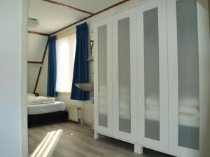 Habitación con 1 dormitorio con 1 cama y cortinas azules. en Vakantiehuis Seahorse en Egmond aan Zee