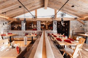 restauracja z drewnianymi sufitami i stołami z czerwonymi serwetkami w obiekcie Anigglhof w mieście Malles Venosta