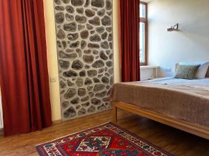 sypialnia z kamienną ścianą i łóżkiem w obiekcie Saryan Guesthouse w mieście Goris