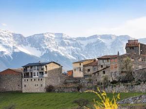 un grupo de edificios en una colina con montañas cubiertas de nieve en Preciosa casa con jardín y piscina, en Bourg-Madame