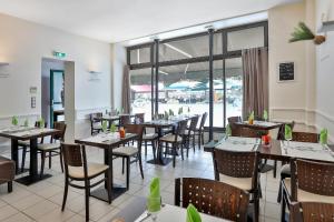 a restaurant with tables and chairs and a large window at Le Coligny in Brantôme