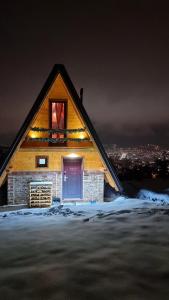 a log cabin with a blue door in the snow at night at Vikendica Tromedja Pale in Pale