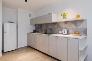 a kitchen with white cabinets and a white refrigerator at ShortStayPoland Grzybowska (B73) in Warsaw