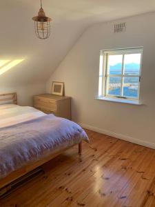 1 dormitorio con cama y ventana en Pink Cottage, en Ballyconneely