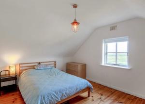a bedroom with a bed and a window at Pink Cottage in Ballyconneely