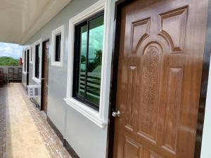 une porte en bois dans un couloir avec une fenêtre dans l'établissement Suncrest Inn, à Butuan