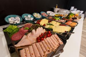 un buffet con carnes y otros alimentos en una mesa en DORMERO Hotel Halle en Halle an der Saale