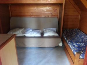 małe łóżko w drewnianej kabinie z 2 poduszkami w obiekcie Camping des Cigales w mieście Aiguèze