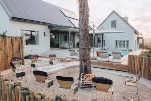 eine Terrasse mit Stühlen und einem Baum vor einem Haus in der Unterkunft Sky Villa Boutique Hotel by Raw Africa Collection in Plettenberg Bay