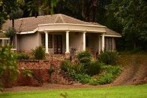a small white house with a brick wall at River Suites Sabie in Sabie