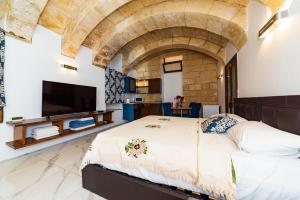 a bedroom with a large bed and a tv at Valletta Old Well Apartments in Valletta