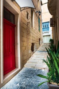 an alley with a red door on a building at Valletta Old Well Apartments in Valletta