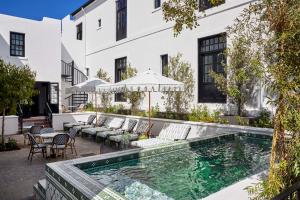 an outdoor swimming pool with chairs and tables and a building at Cape Cadogan Boutique Hotel in Cape Town