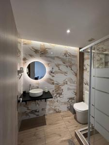 a bathroom with a sink and a toilet and a mirror at Elefsinian Mysteries Apartments in Elefsina +65 photos