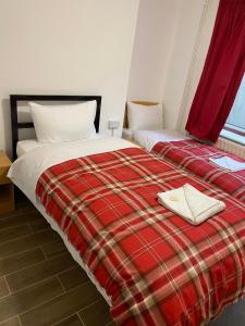 2 camas en una habitación con una manta roja a cuadros en 27 Argyle Square, en Londres