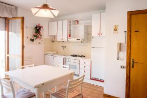 マルチェッリにあるM033 - Marcelli, trilocale in centro fronte mareの白いキャビネット、白いテーブルと椅子付きのキッチン