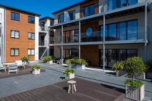 an apartment building with a courtyard with a table and chairs at 11 Woolacombe West - Luxury Apartment at Byron Woolacombe, only 4 minute walk to Woolacombe Beach! in Woolacombe