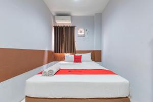 um quarto com uma grande cama branca e um cobertor vermelho em RedDoorz @ Pelajar Pejuang 3 em Bandung