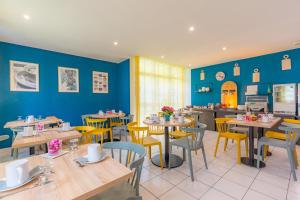 ein Restaurant mit blauen Wänden, Tischen und gelben Stühlen in der Unterkunft Appart'City Classic Bourg-en-Bresse in Bourg-en-Bresse