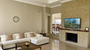 a living room with a white couch and a fireplace at Commodious and Contemporary double home - 2042 in Bulawayo