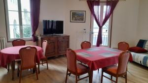 a dining room with a table and chairs and a television at La Bonne Famille in Jumièges