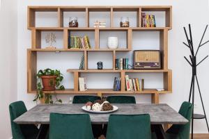 een eettafel met groene stoelen en een boekenplank bij Beautiful new apartment in Petralona in Athene