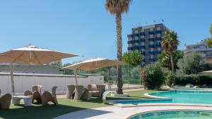 a pool with chairs and umbrellas next to a building at Hotel Sporting in Alba Adriatica