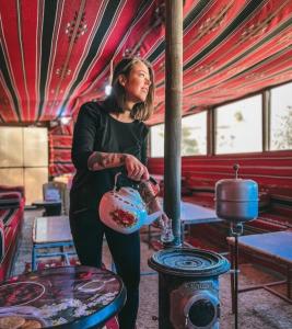 a woman is standing in a room with a stove at 7 Caves Hotel in Al Jāyah